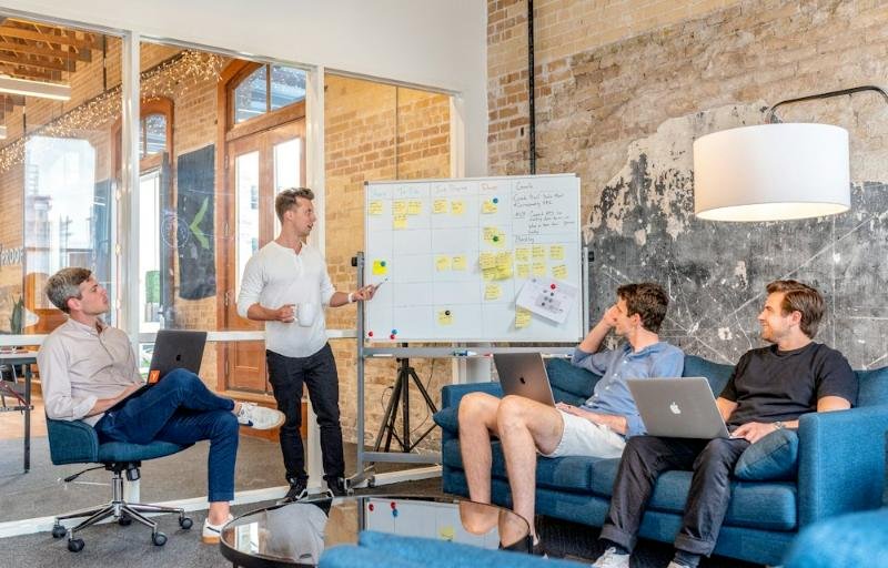 Team meeting around a whiteboard in a brick-walled office