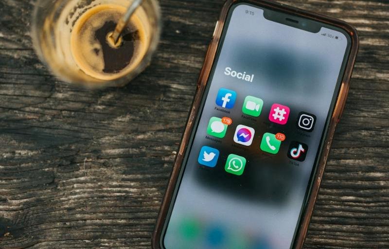 Smartphone showing social media apps beside a coffee